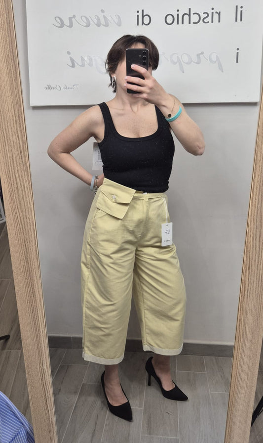 Donna indossa top nero e pantaloni giallo chiaro a vita alta con tacchi neri, moda donna