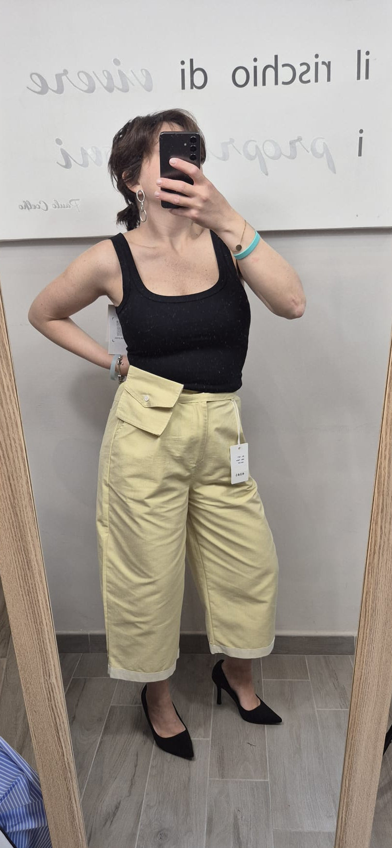 Donna con top nero e pantaloni gialli a vita alta, look moda casual elegante
