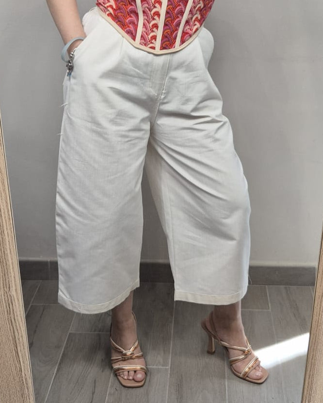 Pantaloni culotte bianchi da donna abbinati a sandali con tacco dorati e corsetto colorato
