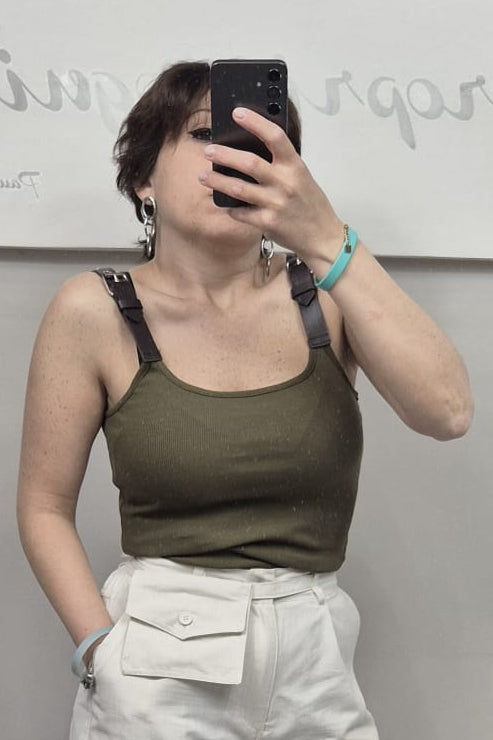 Donna indossa top verde militare con spalline nere e pantaloni bianchi a vita alta