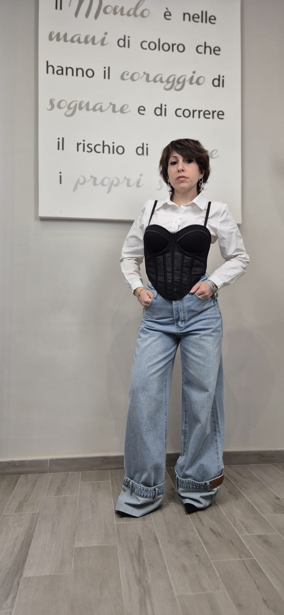 Donna indossa camicia bianca, corsetto nero e jeans larghi a zampa, moda donna casual.