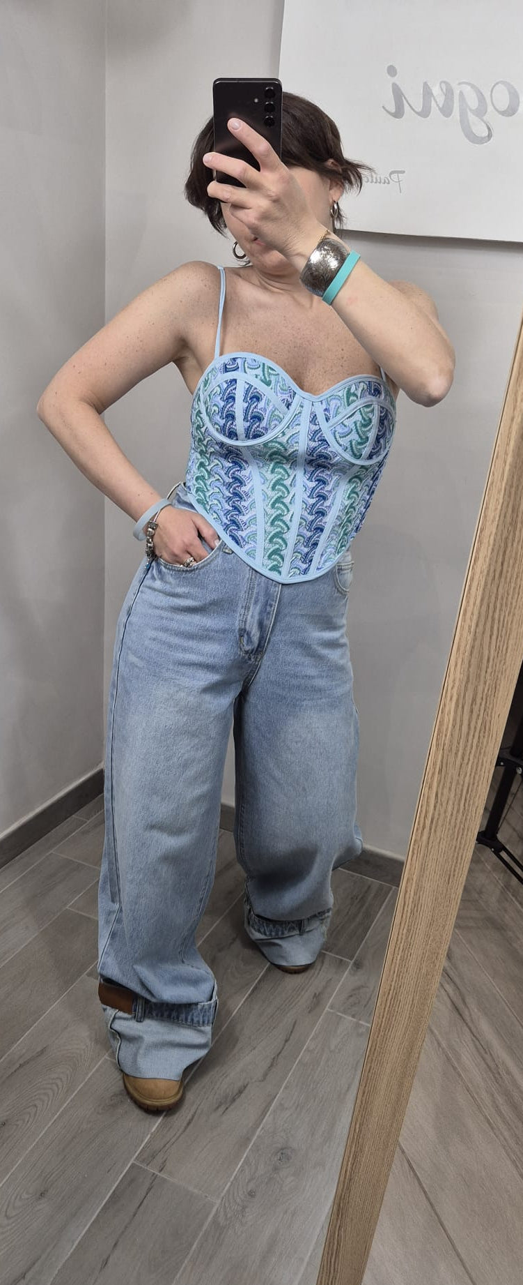 Donna con corsetto azzurro ricamato e jeans larghi, moda donna trendy primavera estate