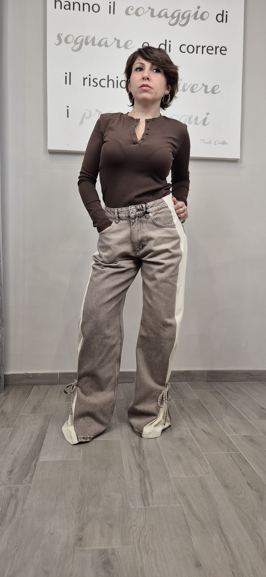Donna con maglia marrone e jeans beige a zampa con bande laterali e lacci, moda donna