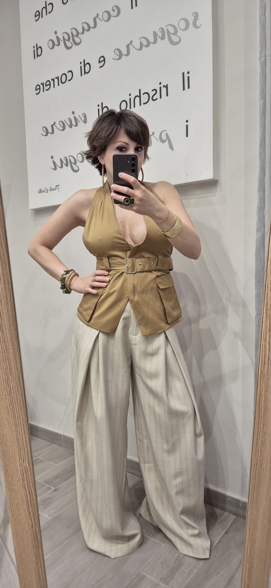 Donna con top halter beige con cintura e pantaloni larghi a righe chiari alla moda