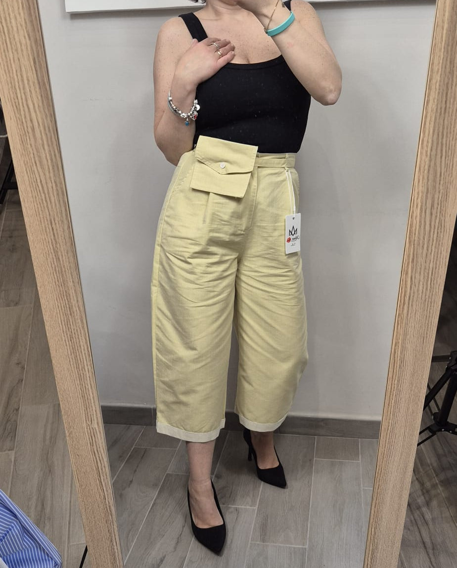 Pantaloni giallo chiaro a vita alta con tasca frontale, top nero, scarpe nere, moda donna elegante.