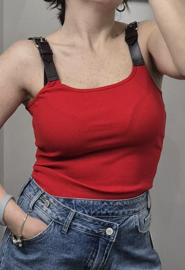 Top rosso da donna con spalline nere e fibbie, abbinato a jeans a vita alta.