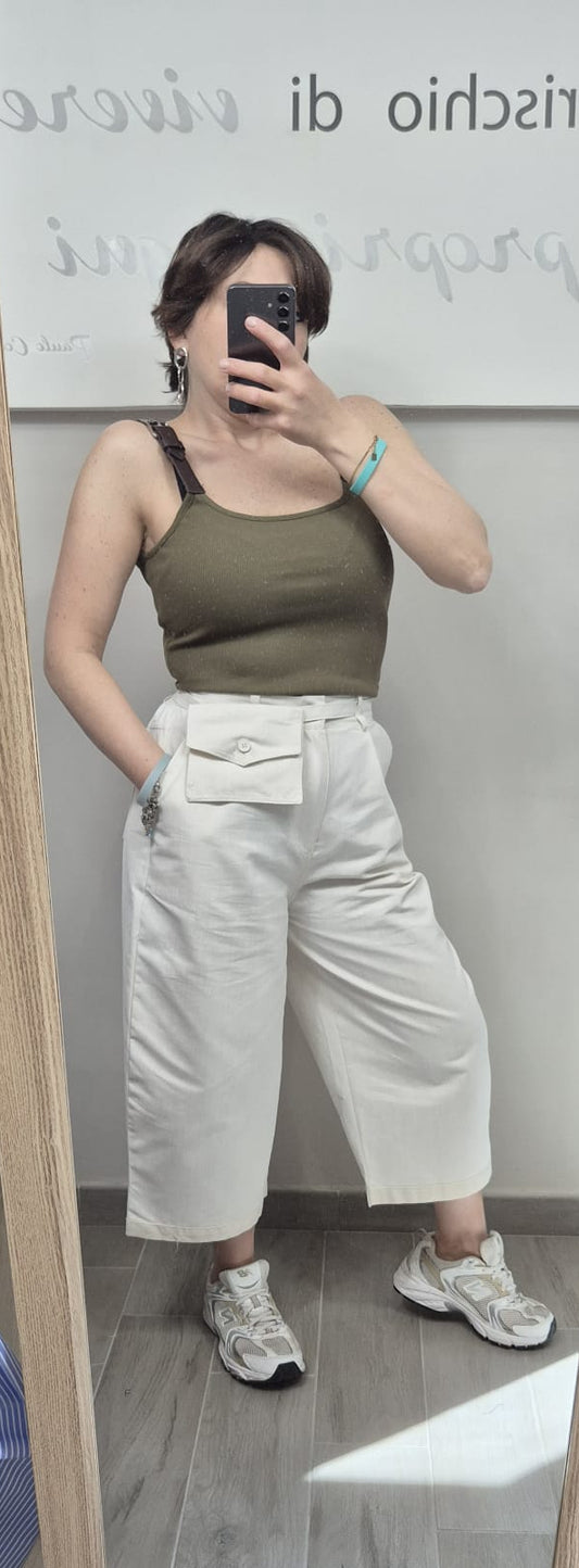 Donna con top verde militare, pantaloni bianchi a palazzo con tasca, sneakers bianche