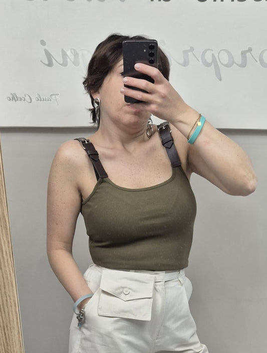 Donna indossa top verde militare con spalline e pantaloni bianchi a vita alta con tasca frontale.