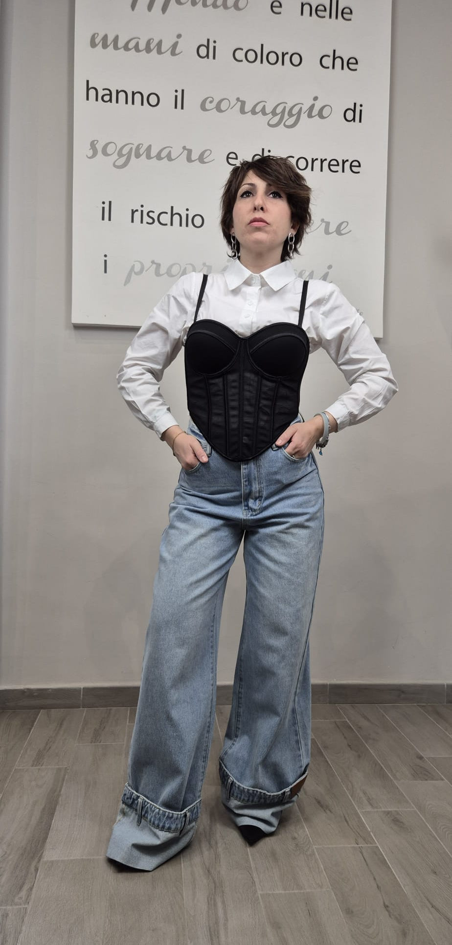 Donna con camicia bianca, corsetto nero e jeans larghi, moda donna moderna.