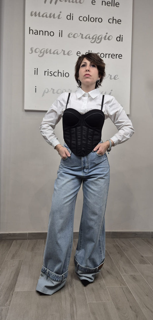 Donna con camicia bianca, corsetto nero e jeans larghi, moda donna moderna.